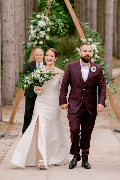 couple smiles as they walk down the aisle