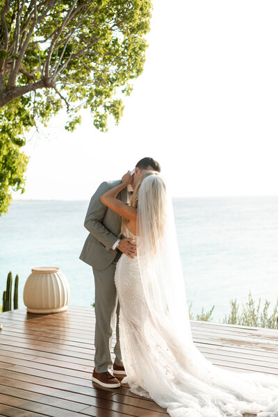 Bride and Groom share a kiss in front of the ocean