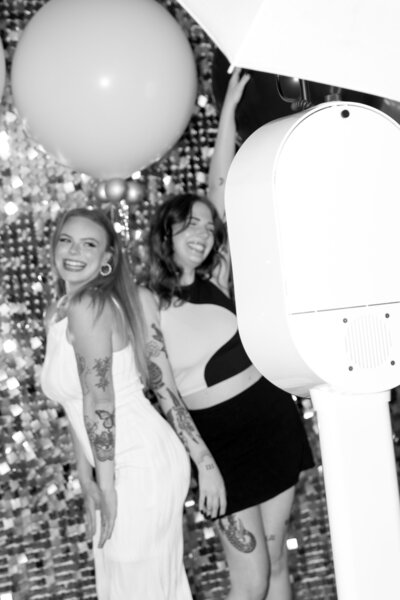 Black and white image of two women having a blast in Always Present photo booth.