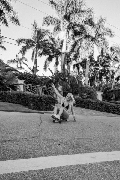 Model sits on skateboard while riding on a palm tree lined street in Sarasota Florida