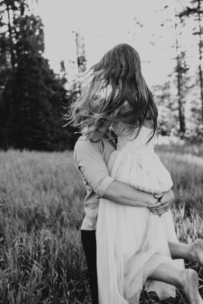 Couples session in Rexburg, Idaho. A man is holding her girlfriend above him, spinning her so you don't see either of their faces.