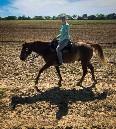 Women riding a horse through a field