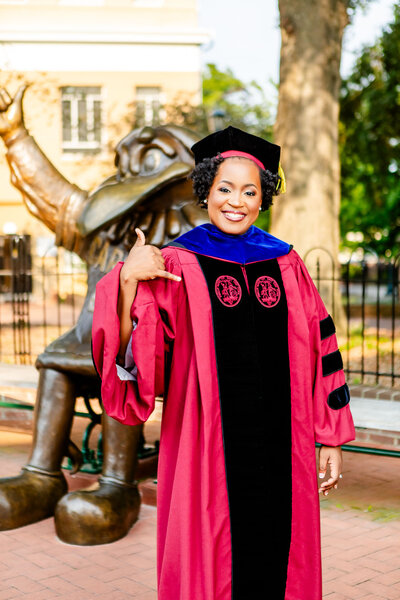 A fashionable Black graduate from the University of South Carolina poses in style, leaning confidently on the stairs. A lifestyle portrait celebrating academic achievement and personal style.