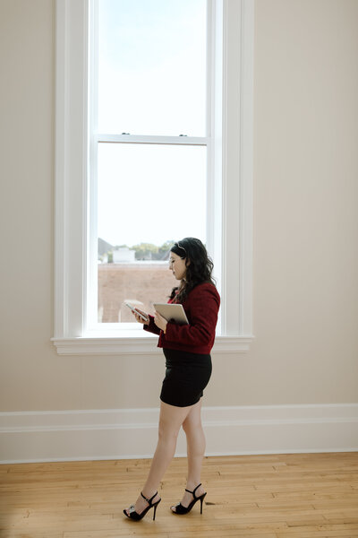 Shanté Gorman, 2024 Female Social Media Manager of the Year, holding an iPad and phone, standing by a large window.