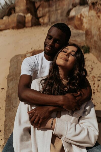 man holding woman from behind in a desert