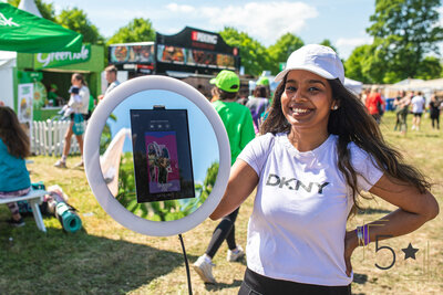 three ladies wearing black with black background getting ready to pose for a photo booth picture, one lady holding the photo booth camera