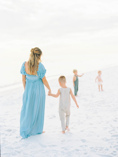 expectant mother walks along the beach with her family in Santa Rosa Beach Florida