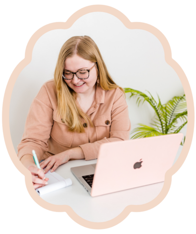 brand photography of blond girl sitting at desk drawing on a note pad next to her pink laptop and plant