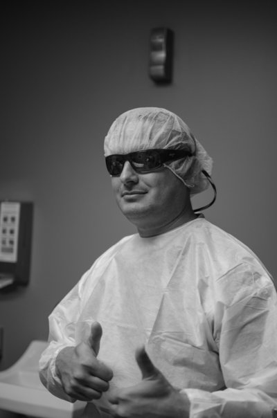Dad wearing sunglasses and scrubs gives a thumbs up before cesarean