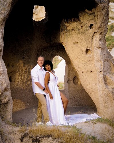Zee & James pose for portrait under archways on the beach