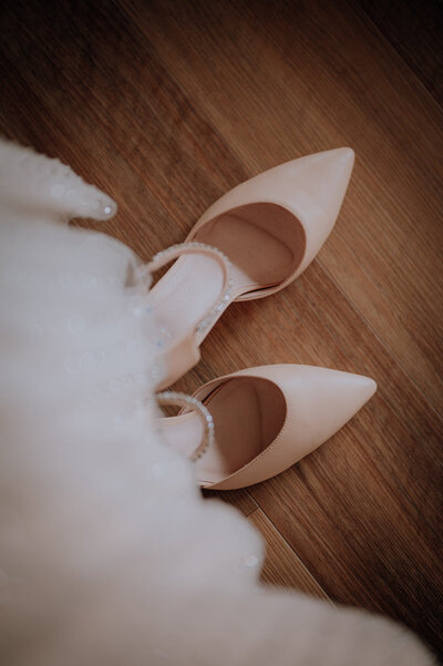 Wedding shoes with a wedding dress out of focus in the foreground
