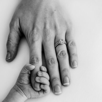a newborn baby hand holds a mothers finger