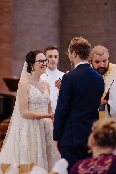 Beaming bride smiles as she holds hands and exchanges vows with her groom. Photo taken by Orlando Wedding Photographer Four Loves Photo and Film.