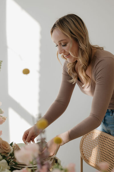 milwaukee event planners, Molly, arranges final details on a wedding table design while smiling.