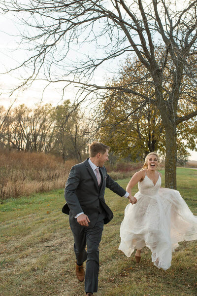 Bride and groom running together during a late fall sunset