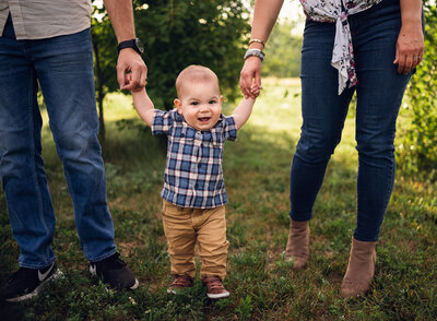 baby boy holding hands with mom and dad