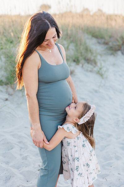 girl snuggling pregnant mom