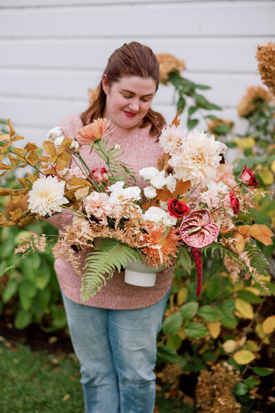 Florist holding fall-inspired floral arrangement
