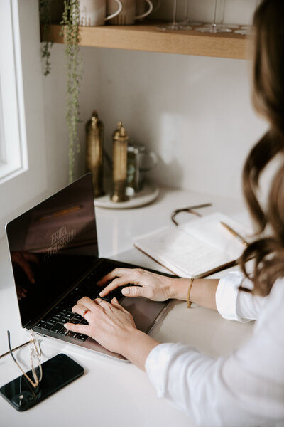 SEO copywriter working on website copywriting services, with an open laptop and notebook on a countertop 