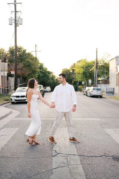Couple holding hands and walking across a city crosswalk