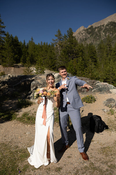 A couple grinning and smiling at the camera, captured in a candid moment by a guest just after their intimate elopement in Breckenridge, Colorado, radiating happiness and love in a spontaneous, joyful moment.