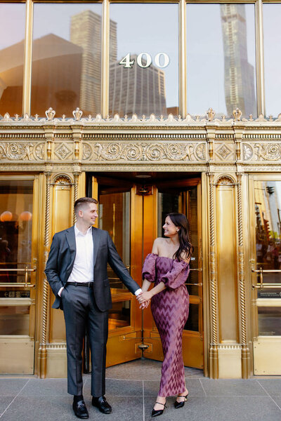 Engaged couple walk out of The Wrigley Building during engagement session