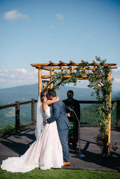 couple on top of hunter mountain having their first kiss as husband and wife