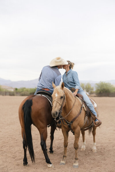 Engaged couple kissing while sitting on their horses in Scottsdale, Arizona