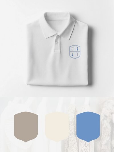 A crisp white polo shirt embroidered with the CT crest monogram in blue, laid flat above brand color swatches in taupe, cream, and blue—perfectly complementing a soft, neutral-toned wardrobe.