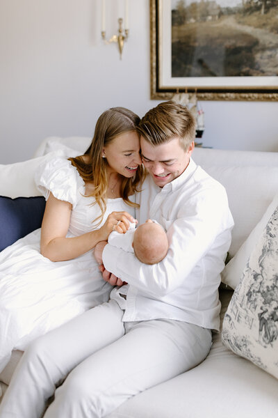 Parents on couch with baby during newborn photos in Carmel, Indiana photographed by Indianapolis Newborn Photographer, Capturing Simplicity Photography