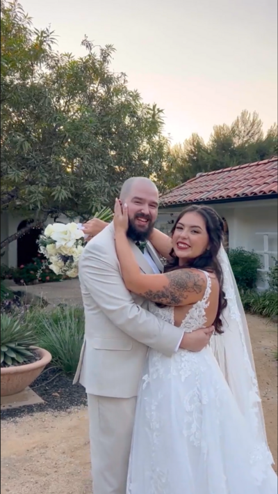 bride and groom embrace smiling at camera