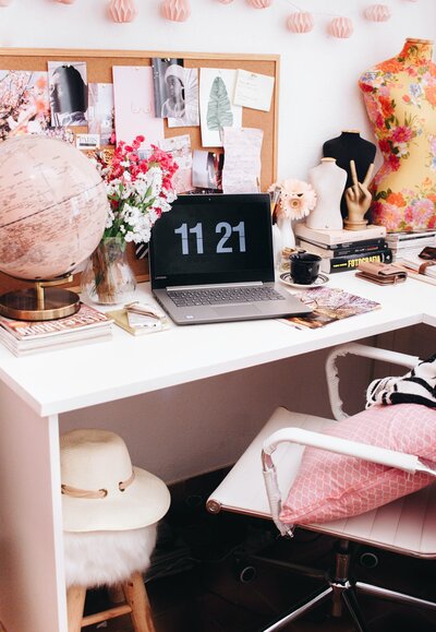 Feminine CEO business owner deskscape with flowers globe and laptop