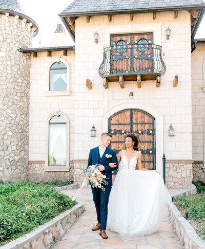 Bride and groom walking in front of castle