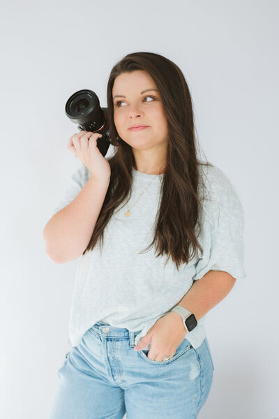 A photo of Michaela looking off to the side and smiling while holding her camera up to the side of her face in Kingsport, TN. Branding Photographer in Northeast, TN