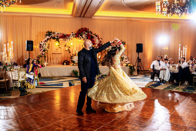 Shannon Lee, an Orlando wedding photographer capturing a beautiful moment of a father and daughter dancing together at the wedding reception, surrounded by floral arrangements and elegant lighting.