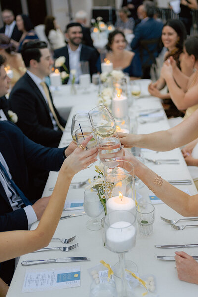 Guests clinking glasses at an elegant outdoor wedding reception with candlelit tables, planned by Eventive Designs in Austin, Texas.