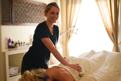 Registered Massage Therapist Noelle Rivet smiling while massaging a client at Wellness On Whyte