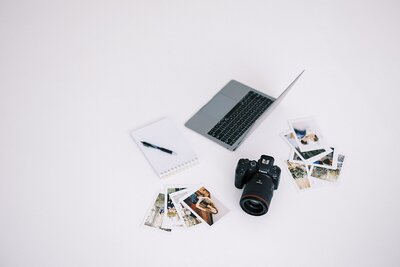 Flat lay of technology and photographic prints with neutral background, captured by Casie Marie Photography during product branding shoot