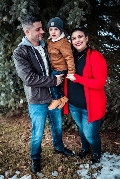 A dad holds up his son and mom holds the little boy's hand