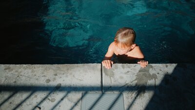 little boy swims to the side of the pool