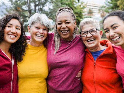Five smiling women in colorful shirts.