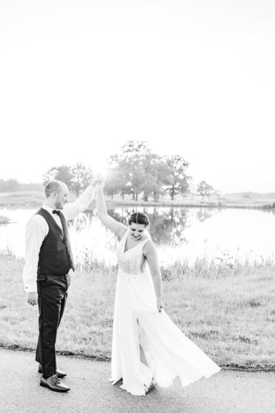 bride and groom holding hands near a pond