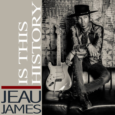 Single cover Is This History musician Jeau James black and white image sitting in front of brick wall with guitar beside him