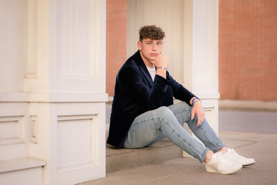 A high school senior boy stands confidently in a scenic Pittsburgh location, dressed in a stylish yet casual outfit. He gazes into the camera with a relaxed expression, capturing his personality and individuality. The city's skyline or a natural backdrop enhances the portrait, adding a timeless and authentic feel.