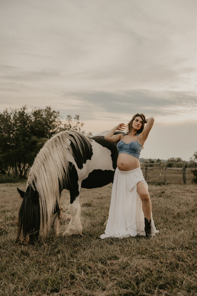 Expecting mother in earth-toned dress holding baby bump during soft, natural light maternity photography session – Mendham, NJ