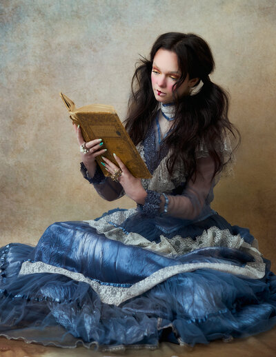 Young woman in a designer gown for a couture portrait wearing a crown holding a mirror seeing her reflection
