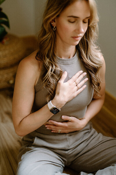 Woman practicing breath work with her hands on her chest at Alyn Wellness Studio