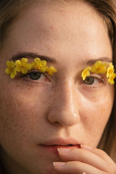 woman with yellow flower petals above her eyebrows