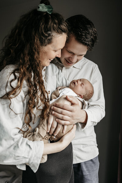 mama en papa die hun baby vasthoudt en liefdevol aankijkt