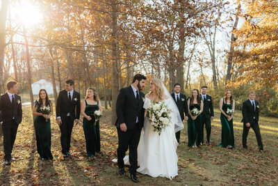 A couple walking with their wedding party at their fall wedding.
